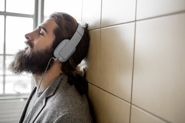 Junger bärtiger Mann hört Musik mit Kopfhörern - ZOCF000100
