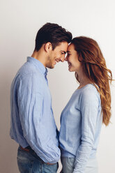 Glückliches junges Paar steht von Angesicht zu Angesicht vor einem weißen Hintergrund - CHAF001654
