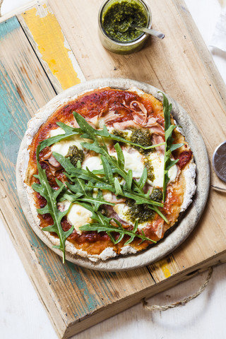 Hausgemachte glutenfreie Pizza mit Mozzarella, Rucola-Pesto und frischem Rucola, lizenzfreies Stockfoto