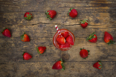 Glass of strawberry smoothie and strawberries on dark wood - LVF004811