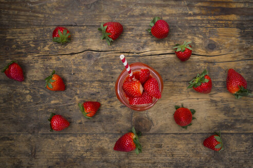 Glas mit Erdbeer-Smoothie und Erdbeeren auf dunklem Holz - LVF004811