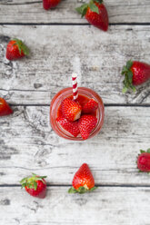 Glass of strawberry smoothie and strawberries on wood - LVF004812