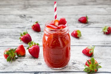 Glass of strawberry smoothie and strawberries on wood - LVF004813