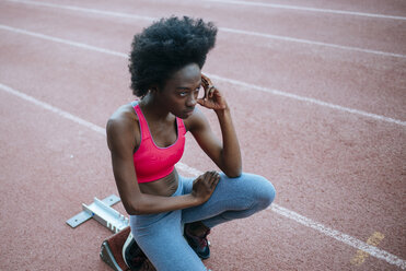 Female athlete taking position on her marks to start off the run