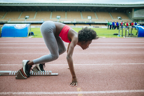 Junger schwarzer Sportler bereitet sich auf Rennen im Stadion vor - KIJF000375