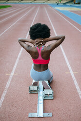 Side view of female teen athlete in sports bra and tights successfully  finishing race on track at stadium Stock Photo