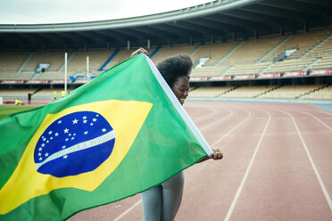 Junger schwarzer Sportler im Stadion mit brasilianischer Flagge - KIJF000378