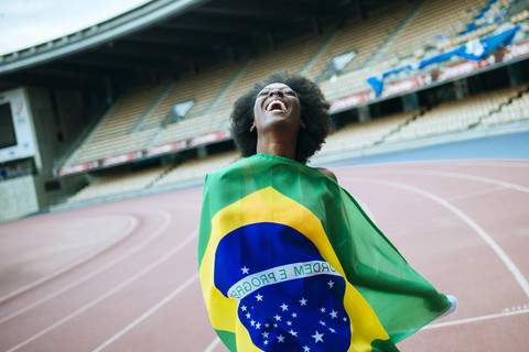 Junger schwarzer Sportler im Stadion mit brasilianischer Flagge, lizenzfreies Stockfoto