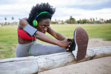 ng black athlete listening music with headphones while warming up - KIJF000390