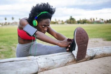 ng schwarzer Sportler, der beim Aufwärmen mit Kopfhörern Musik hört - KIJF000390