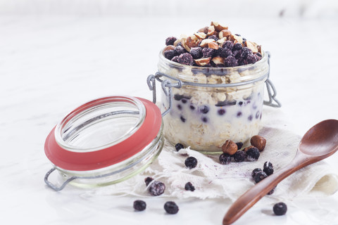 Einmachglas mit Overnight Oats mit Ananas, Kokosnuss, Chia-Pudding, Haselnüssen und Beeren, lizenzfreies Stockfoto