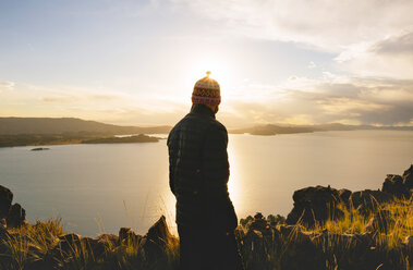 Peru, Amantani Island, back view of man enjoying sunset from Pachamama peak - GEMF000882