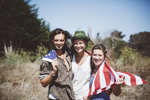 Porträt von drei lächelnden Hippies mit US-Flagge in der Natur - GIOF000899