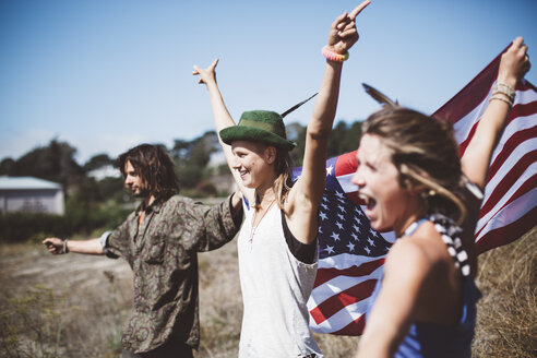 Drei jubelnde Hippies mit US-Flagge in der Natur - GIOF000908