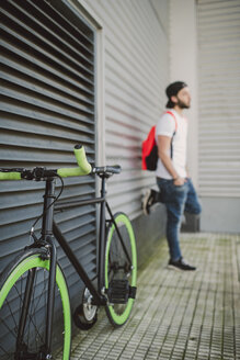 Fixie-Bike und junger Mann lehnt an der Wand - RAEF001130