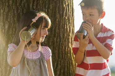 Kleiner Junge und Mädchen spielen mit Blechdose Telefon in der Natur - ZOCF000116