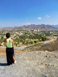 Oman, Dhakiliya, junge Frau schaut nach Bahla, Fort Bahal im Hintergrund, Al Hajar al Gharbi-Gebirge - AMF004862