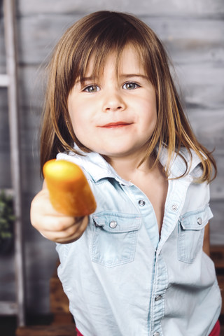 Porträt eines kleinen Mädchens, das einen Eislutscher anbietet, lizenzfreies Stockfoto