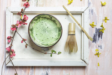 Matcha-Tee in Schale, mit Matcha-Pulver, Löffel und Chasen und rosa Blumen - SBDF002861