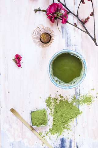 Matcha-Tee in Schale, mit Matcha-Pulver, Löffel und Chasen und rosa Blumen, lizenzfreies Stockfoto