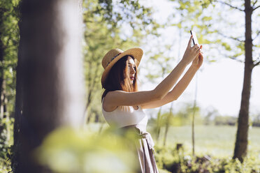 Junge Frau macht Selfie mit Smartphone in der Natur - GIOF000926