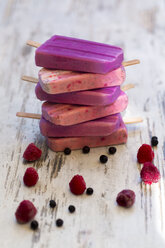 Stack of homemade blueberry ice lollies and raspberry ice lollies with chia - SARF002716