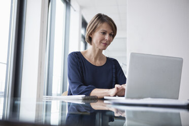 Geschäftsfrau arbeitet an einem Laptop am Bürotisch - RBF004416