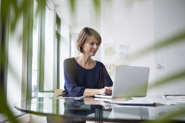 Geschäftsfrau arbeitet an einem Laptop am Bürotisch - RBF004422