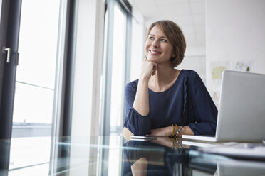 Smiling businesswoman at office desk - RBF004425