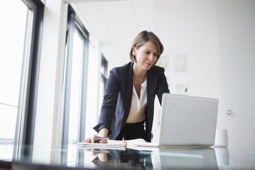 Geschäftsfrau arbeitet an einem Laptop am Bürotisch - RBF004426