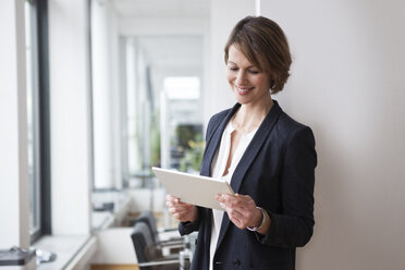 Smiling businesswoman holding digital tablet in office - RBF004429