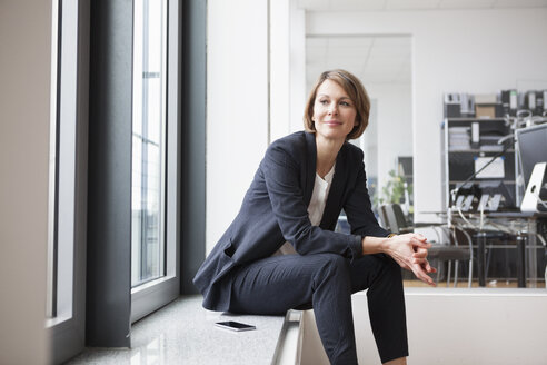 Geschäftsfrau sitzt am Fenster - RBF004431