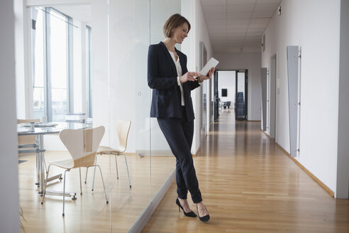 Geschäftsfrau benutzt digitales Tablet in Bürohalle - RBF004444