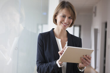 Lächelnde Geschäftsfrau mit digitalem Tablet im Büro - RBF004445