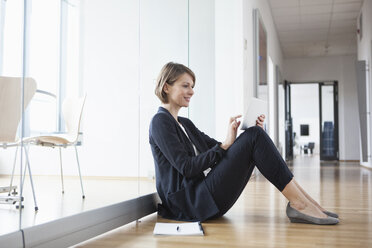 Geschäftsfrau sitzt im Büro und benutzt ein digitales Tablet - RBF004450