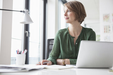 Businesswoman at office desk thinking - RBF004455