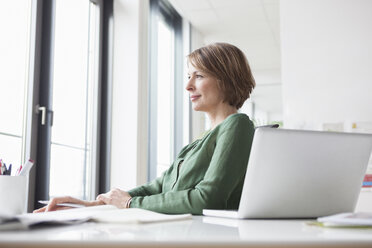 Businesswoman at office desk thinking - RBF004456