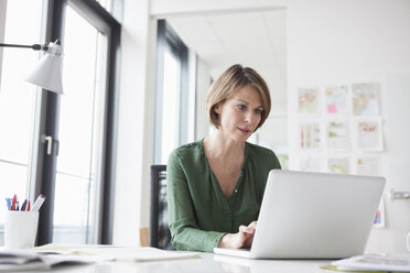 Businesswoman working on laptop at office desk - RBF004462