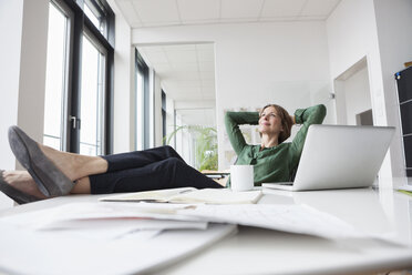 Businesswoman relaxing at office desk - RBF004466