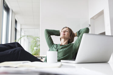 Geschäftsfrau entspannt sich am Bürotisch - RBF004467