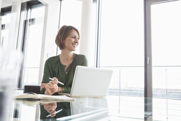 Smiling businesswoman at office desk - RBF004468