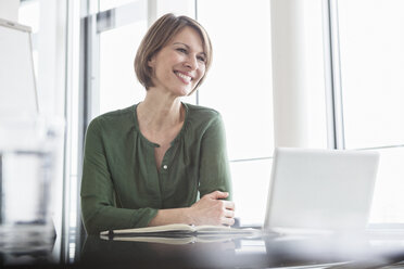 Smiling businesswoman at office desk - RBF004470