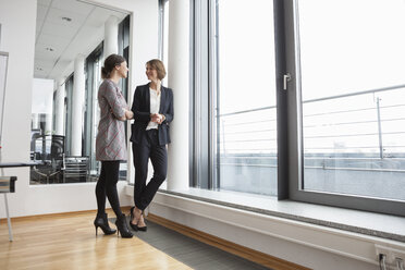 Zwei Geschäftsfrauen unterhalten sich am Fenster - RBF004484