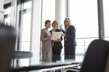 Drei Geschäftsfrauen besprechen Dokumente am Fenster - RBF004486