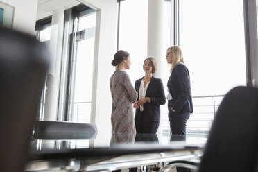 Drei Geschäftsfrauen unterhalten sich am Fenster - RBF004487