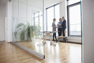 Drei Geschäftsfrauen unterhalten sich am Fenster - RBF004505