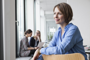 Smiling businesswoman with colleagues in background - RBF004507