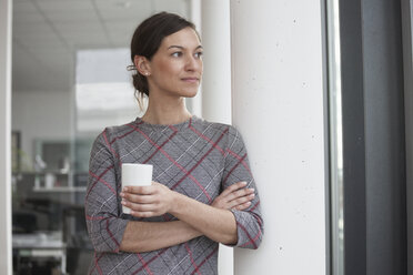 Businesswoman holding cell phone looking sideways - RBF004524