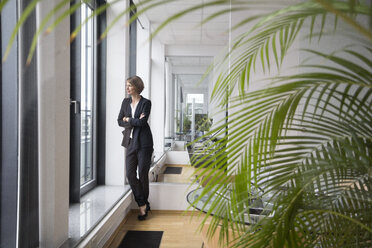 Businesswoman in office looking out of window - RBF004527