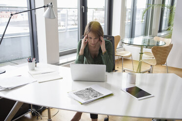 Concentrated businesswoman working on laptop at office desk - RBF004531